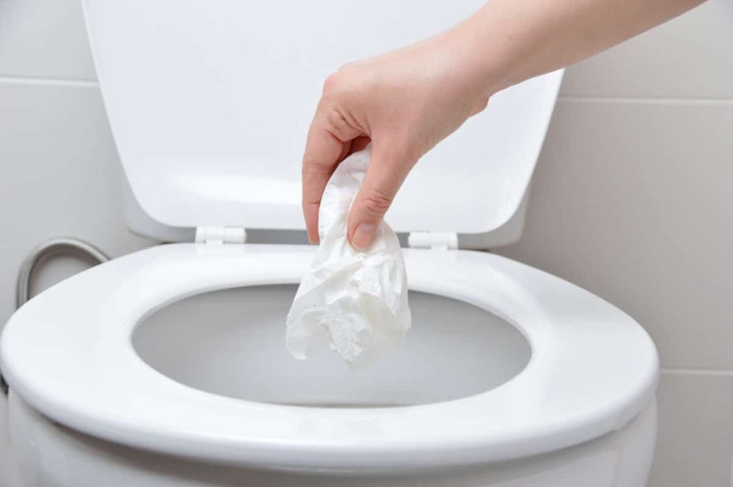 une femme en train de jeter des dÃ©chets dans les toilettes