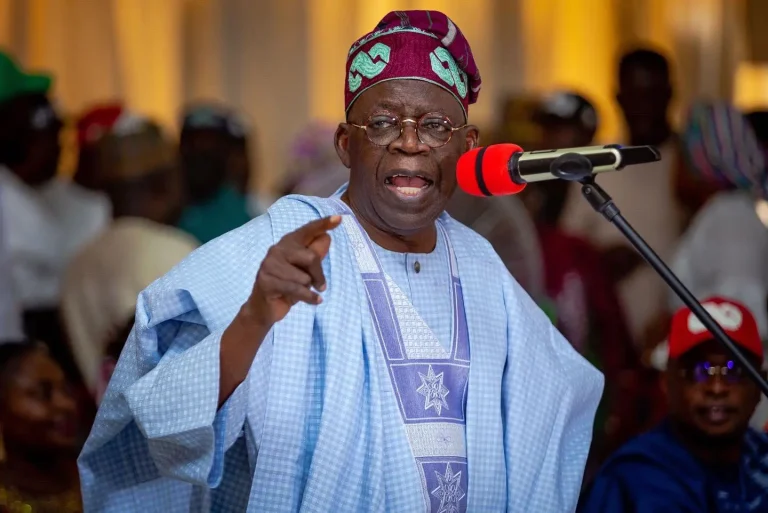 Le président nigérian Bola Ahmed Tinubu s’exprimant lors d’un rassemblement à Abuja. Vêtu d’un agbada traditionnel, il défend avec vigueur sa vision politique face aux critiques croissantes.
