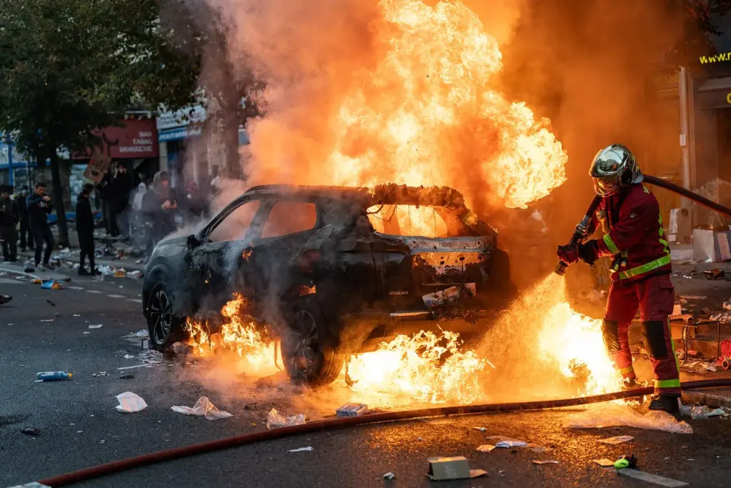 Des pompiers éteignent une voiture incendiée à Paris le 17 octobre 2026