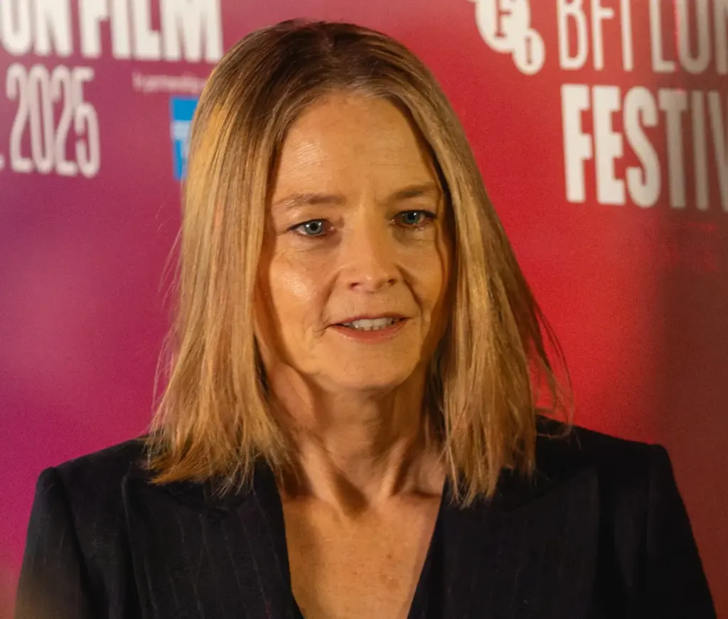 Portrait de Jodie Foster devant un fond rose en 2025