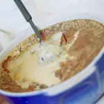 Teurgoule dans un plat bleu avec sa croûte dorée et une louche
