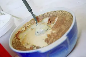 Teurgoule dans un plat bleu avec sa croûte dorée et une louche