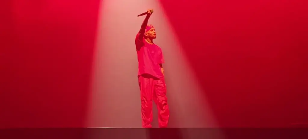 Chris Brown au micro sur une scène éclairée en rouge à Londres en mars 2023, photographie d’archive.