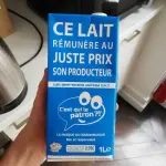Brique de lait bleue C’est qui le Patron ?! tenue dans une main